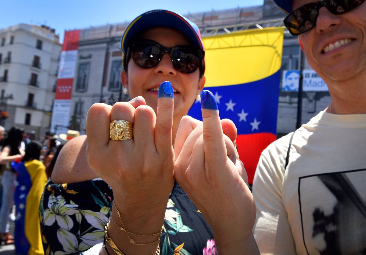Dos venezolanos muestran sus dedos meñiques pintados que son el símbolo de que han participado en el referéndum.