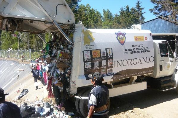 Camión municipal descarga basura en relleno.