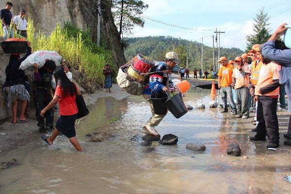 PERSONAS CRUZAN el tramo dañado para trasbordar o trasladar su mercadería.