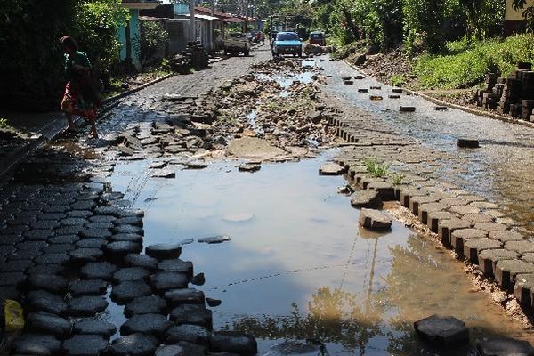 Las aguas servidas corren a flor de tierra en una calle.