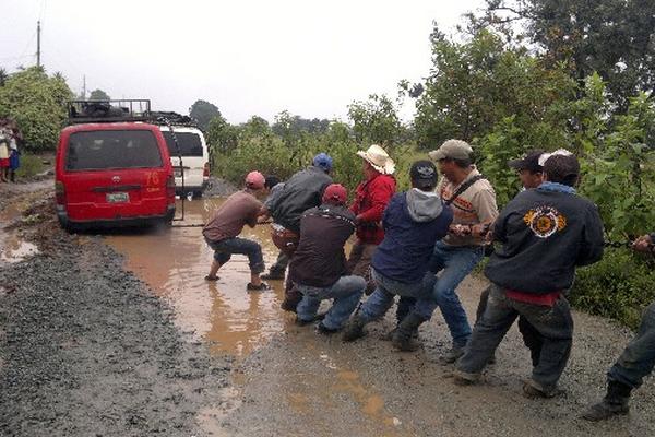 Vecinos  halan un    microbús atascado.