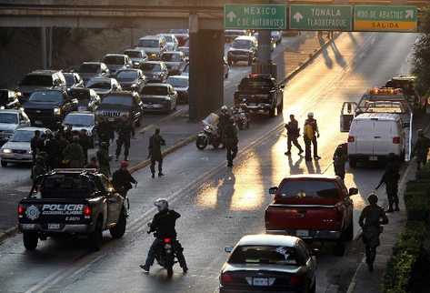 Autoridades mexicanas en el lugar donde fueron encontrados tres vehículos en Guadalajara  encuyo interior habían 23 cadáveres. (EFE).