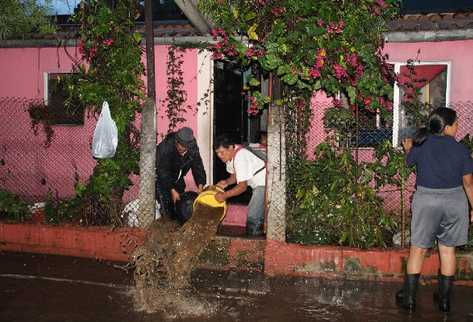 Pobladores sacan    agua de una vivienda.