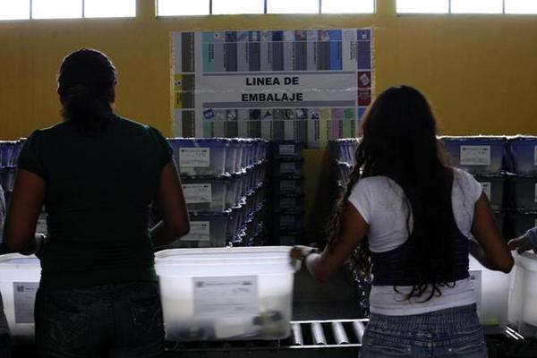 Voluntarios organizan el material a utilizar en la segunda vuelta. (Foto Prensa Libre: EFE)