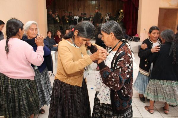 Varias personas de la tercera edad  bailan al ritmo de las notas de la banda militar de Cobán.