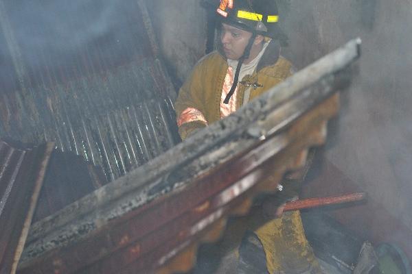 Un bombero camina entre los escombros de la vivienda.