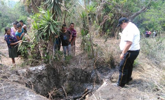 Bomberos revisan la fosa en que fueron encontrados los cuerpos calcinados. (Foto Prensa Libre: Erick Ávila)