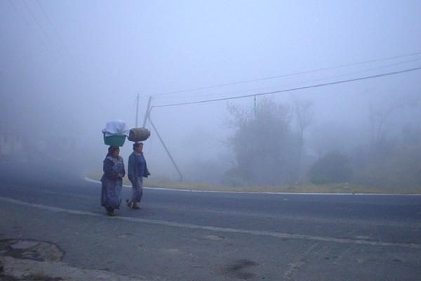 Dos mujeres caminan abrigadas por una calle de  Xelajú, debido a la baja temperatura.