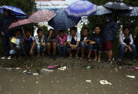 Jóvenes nepalíes esperan en fila para solicitar trabajo en Corea del Sur bajo una fuerte lluvia en Katmandú. (Foto Prensa Libre: EFE)