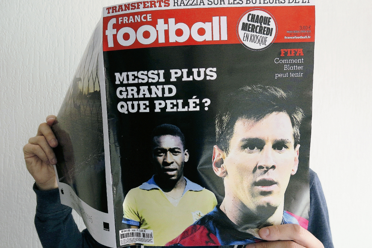 Un hombre sostiene la revista France Football,  que abre un debate cada vez más patente en el deporte rey, "¿Es Messi más grande que Pelé?". (Foto Prensa Libre: EFE)