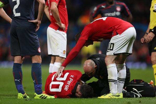 Robin Van Persie mientras es atendido por sus compañeros y cuerpo médico en el duelo ante Olympiakos. (Foto Prensa Libre: AP)