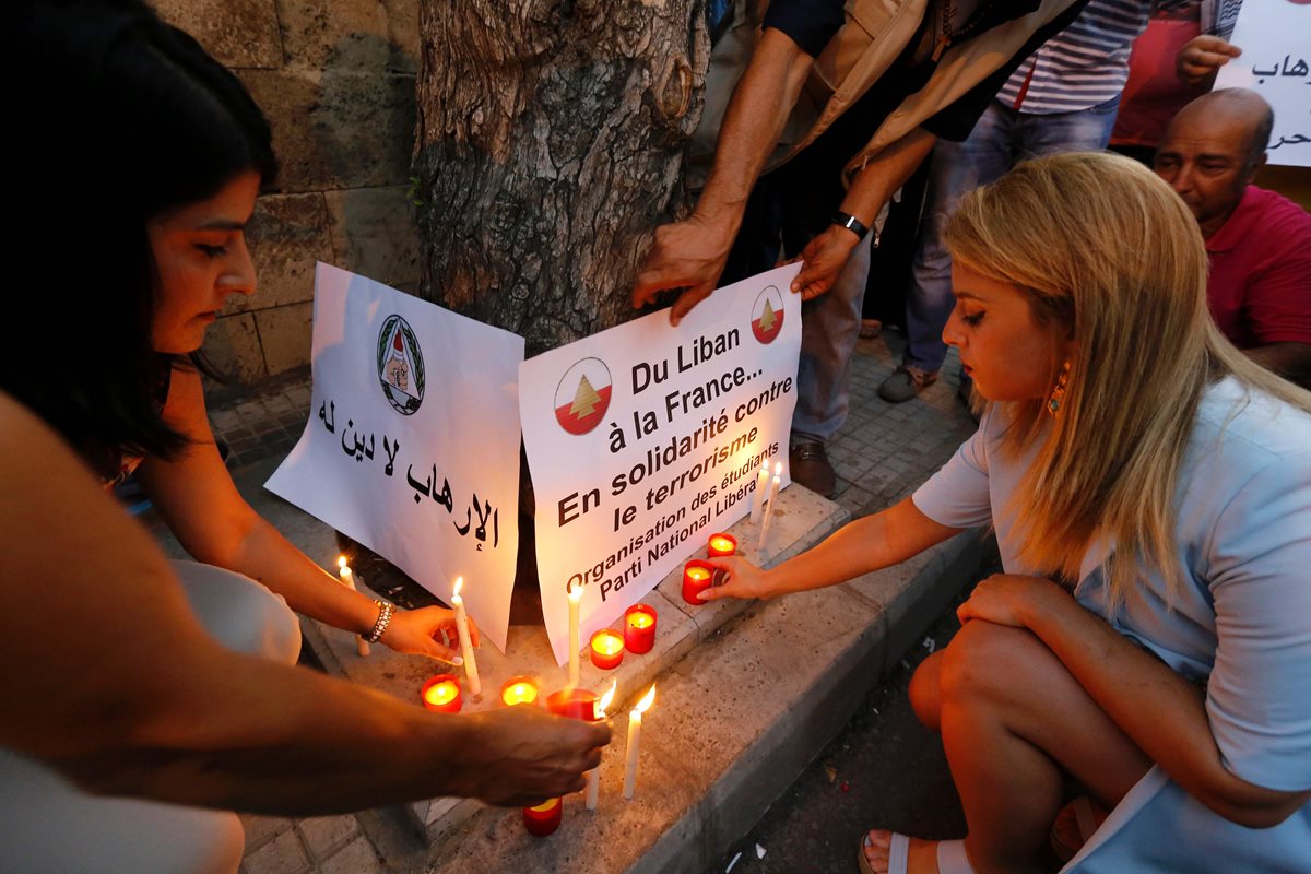 Dos mujers encienden velas frente a la embajada de Francia en Líbano, en homenaje a las víctimas. (Foto Prensa Libre: AP).