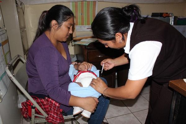 Una enfermera del centro de Salud de la cabecera vacuna al  hijo de Evelin Tacatic.