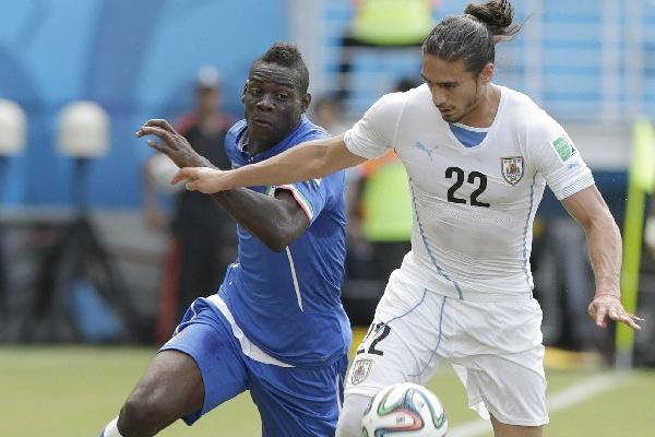 Mario Balotelli compite por la posesión del balón contra el uruguayo Martin Caceres. (Foto Prensa Libre: EFE)