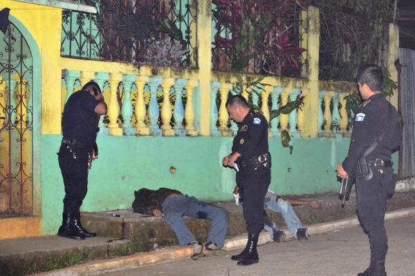 Agentes de la PNC observan los cadáveres.