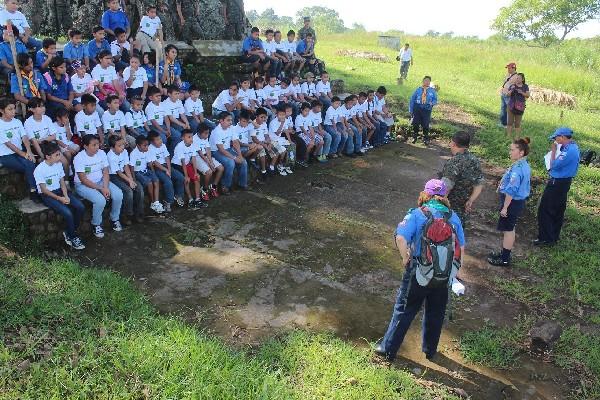 Instructores  brindan   información a varios niños sobre una de las  actividades de los scouts.