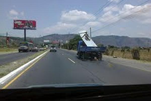 Un obrero viaja encima de un lio de láminas en la carretera al Pacífico. (Foto Prensa libre. Carlos Hernández)