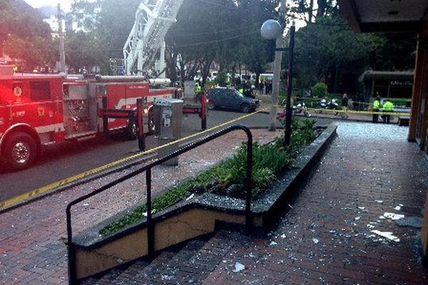 Integrantes de los Bomberos de Bogotá retiran los vidrios rotos de las edificaciones cercanas a una comisaría policial. (Foto Prensa Libre: EFE)