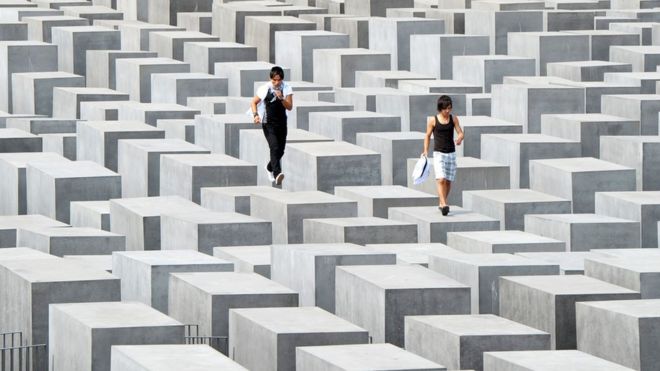 Dos visitantes caminan sobre los pilares del monumento al Holocausto en Berlín. AFP