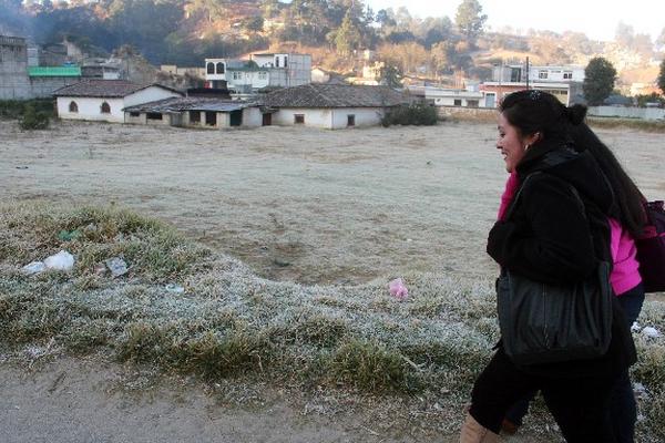 Una señora camina junto a un campo, donde se observa la escarcha que cayó la madrugada de ayer en Quetzaltenango, al estar a dos grados bajo cero,