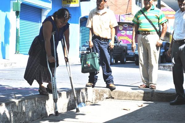 Una mujer que utiliza muletas para caminar enfrenta dificultades para bajar de una banqueta, pues esta es muy alta. (Jorge Tizol)<br _mce_bogus="1"/>