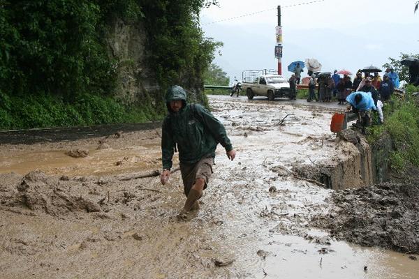 Un turista  camina entre el lodo del derrumbe en el kilómetro 141, hacia San Jorge la Laguna, Sololá.