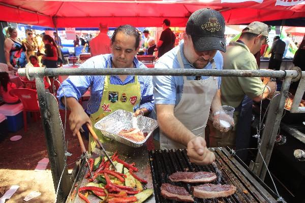 Competidores preparan  carne de res y vegetales a la parrilla, para la degustación.