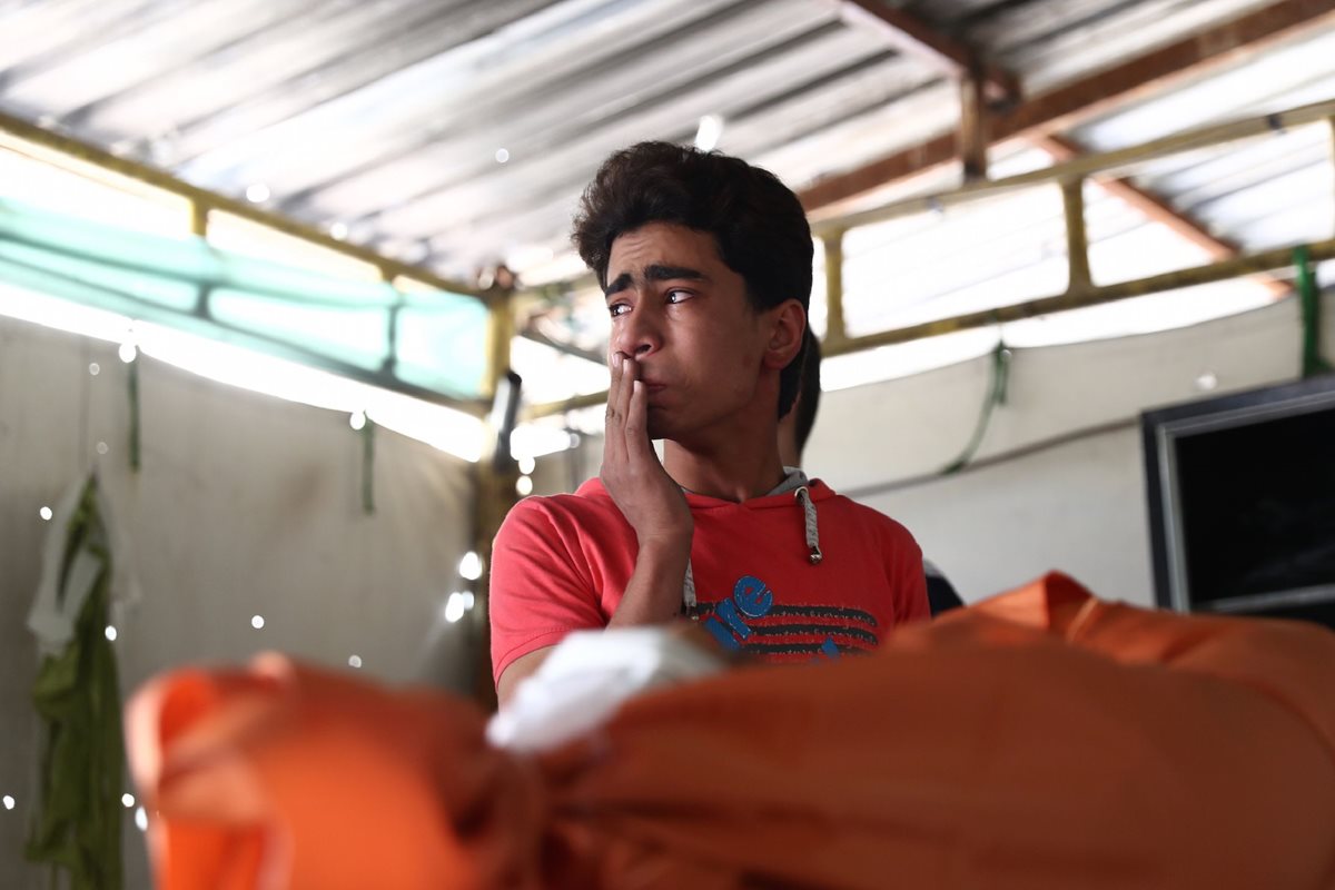 Un joven sirio llora al identificar el cuerpo de su hermano muerto en uno de los bombardeos. (Foto Prensa Libre: AFP).