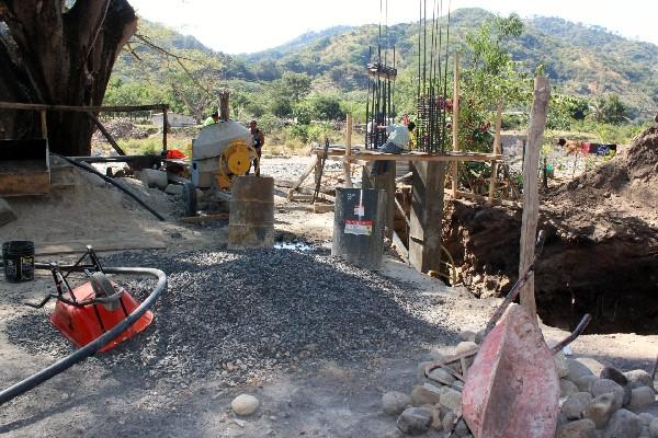 Constructores edifican las bases de puente peatonal sobre el río Motagua.