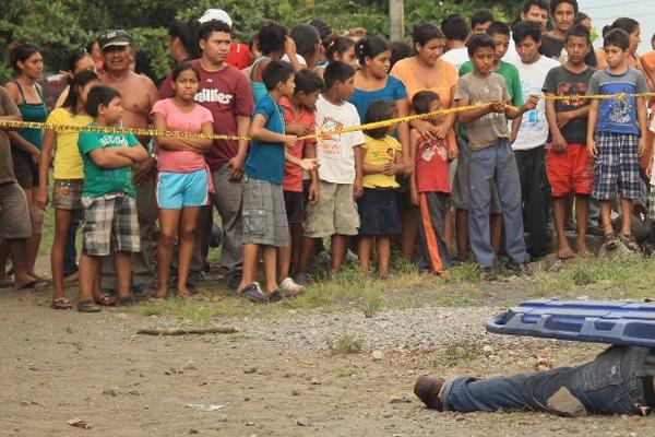 Curiosos observan el cadáver de Pedro Chinchilla Cruz, quien murió baleado en Masagua. (Foto Prensa Libre: Enrique Paredes)