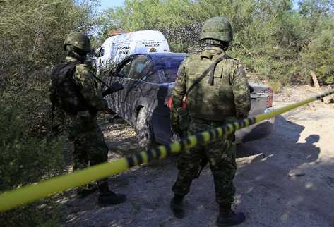 Soldados del ejército mexicano cerca del lugar donde investigadores forenses y el personal de inspección las fosas con restos humanos. (Foto Prensa Libre: AFP)