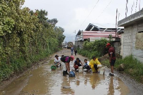 Familias retiran  lodo de  camino.