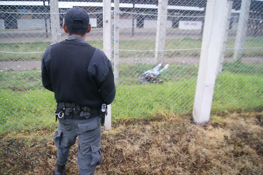 Un guardia del Sistema Penitenciario observa el cuerpo del reo fallecido al intentar escapar de Pavón. (Foto Prensa Libre: Cortesía del SP)