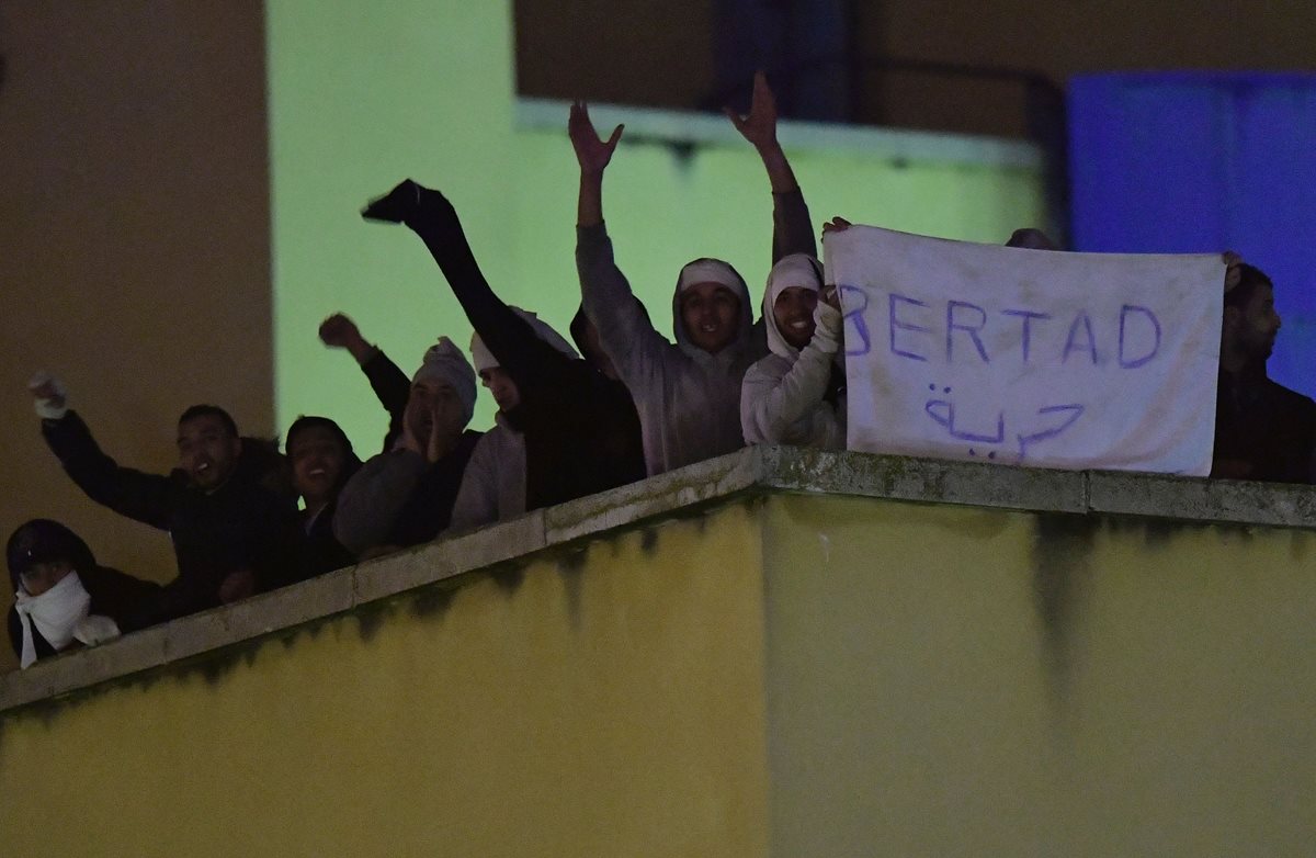 Decenas de migrantes gritan consignas en el centro de retención de Madrid, España. (Foto Prensa Libre: AFP).