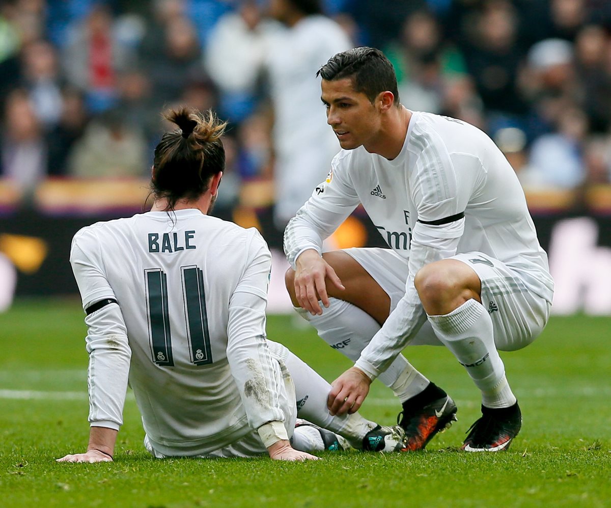 El portugués Cristiano Ronaldo conversa con Gareth Bale que se queda sentado en la gramilla del Bernabéu luego de lesionarse. (Foto Prensa Libre: EFE)