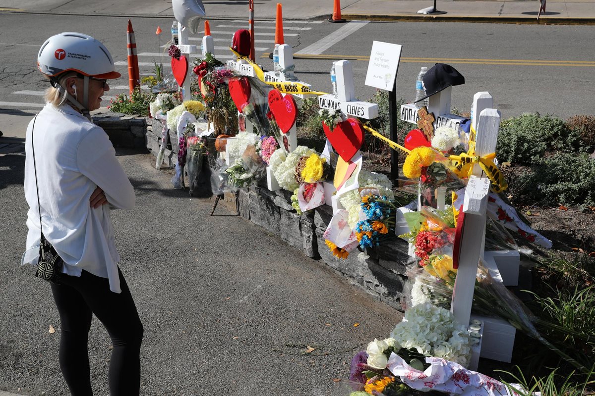 Personas observan el pequeño homenaje con flores y una camiseta argentina en una barricada policial en Nueva York. (EFE).