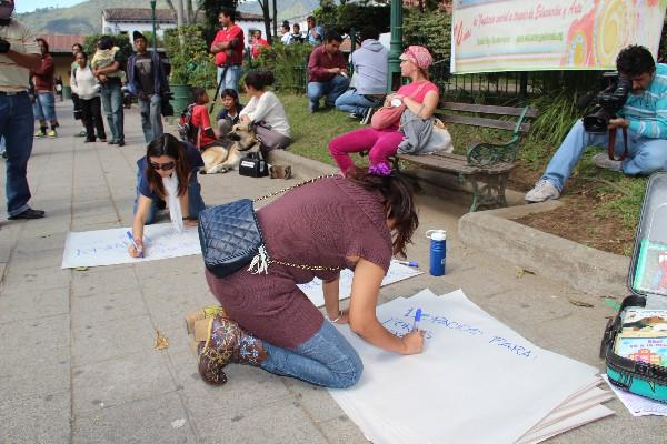 antigueñas pintan carteles para exigir que se respete el patrimonio cultural.