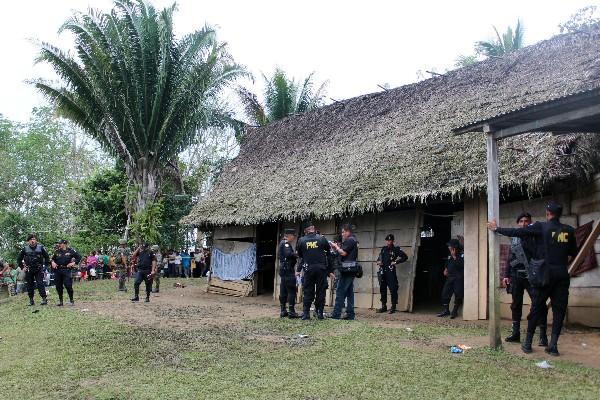 Policías resguardan el lugar donde murieron ocho personas, entre ellas dos niñas, de 5 años y tres meses de edad, en San Luis, Petén.