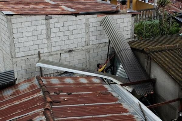 Un vecino intenta recuperar una lámina  agitada por el viento. (Foto Prensa Libre: Víctor Chamalé)