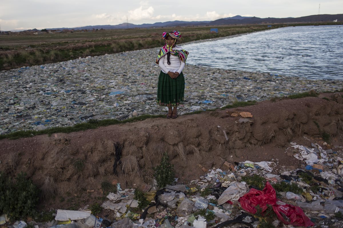 La activista Maruja Inquilla posa para una fotografía frente a una parte del lago llena de basura. (Foto Prensa Libre: AP)