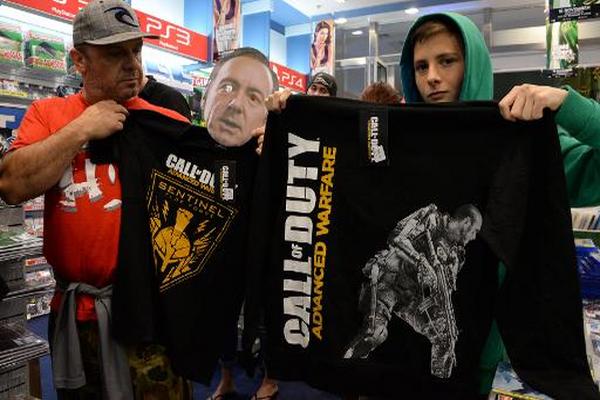 Dos compradores posan mientras hacen cola para comprar la última versión de Call of Duty en Sidney, Australia. (Foto Prensa Libre: AFP)