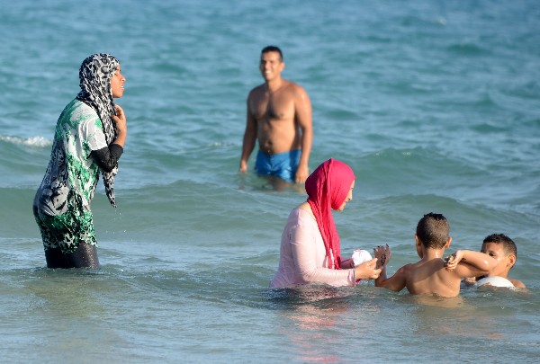 Dos mujeres musulmanes totalmente cubiertas se baña en una playa.(Foto Prensa Libre: AFP)