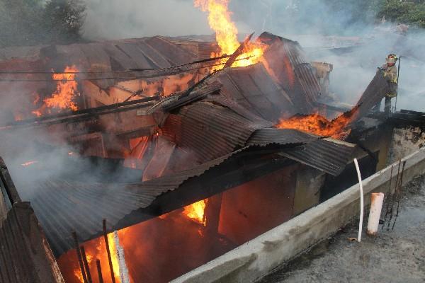 Socorristas intentan  apagar las llamas que consumen mercadería de comercios y enseres de  viviendas, en Mazatenango, Suchitepéquez.