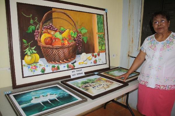 Aurora Mencos posa junto a   sus cuadros,  durante  exhibición en un  colegio de Jutiapa.