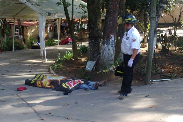 Socorrista observa el cadáver de  César Amílcar Izaguirre García,  en el patio de   vivienda,   en el cantón Reforma, San Lucas Sacatepéquez.