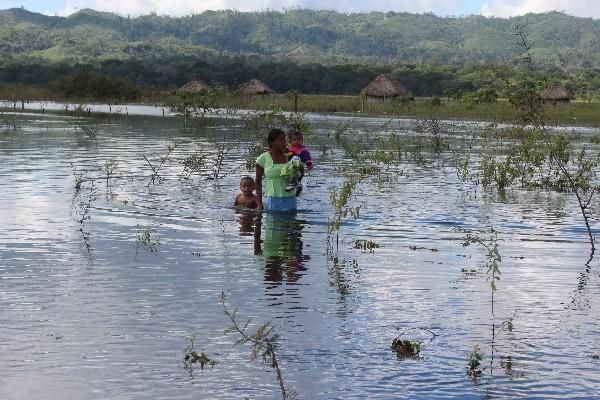 Una madre con sus dos hijos camina entre el agua que se salió de la cuenca de la laguna Guayacán, en  la comunidad Guayacán  Sierra del Lacandón.