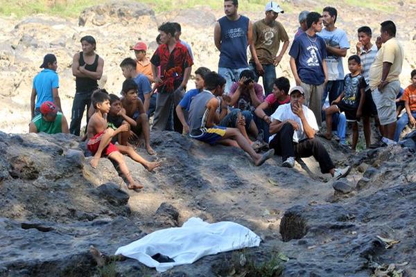 Vecinos del parcelamiento Caballo Blanco, Retalhuleu, observan el cadáver del menor ahogado en el río Ocosito. (Foto Prensa Libre: Rolando Miranda)