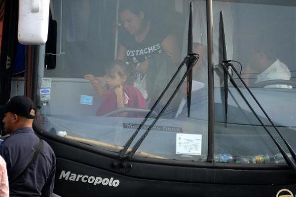 Una mujer baja e del autobus con su hija deportada por EE. UU. en San pedro Sula, Honduras. (Foto Prensa Libre: AFP)