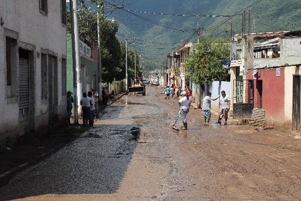 Vecinos de Jocotenango retiran el lodo  en la Calle Ricardo Arjona.