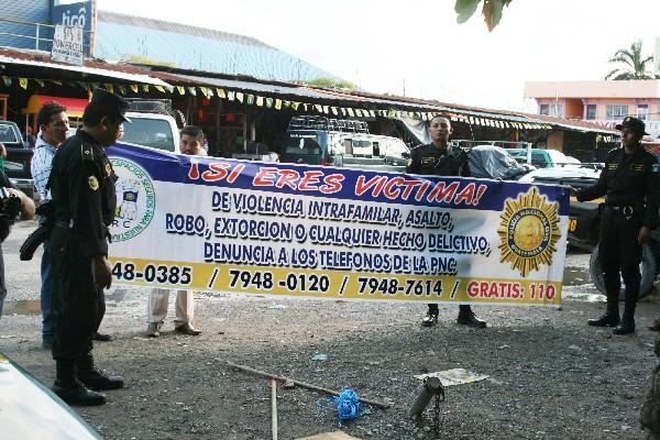 Policías y miembros de la Junta Local de Seguridad de Puerto Barrios sostienen una de las mantas que se  colocaron en puntos estratégicos.